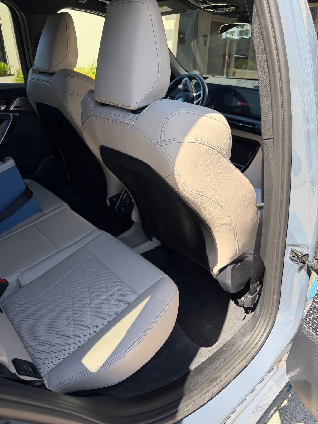 Rear passenger-side footwell of a grey BMW X1 before detailing, with light lint on the carpet