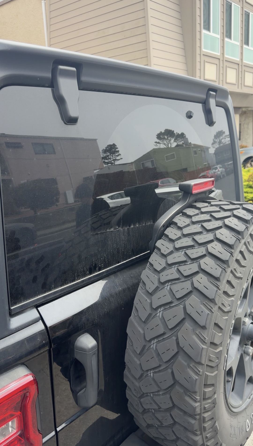 Jeep Wrangler rear glass with dried water-spot residue above the spare tyre