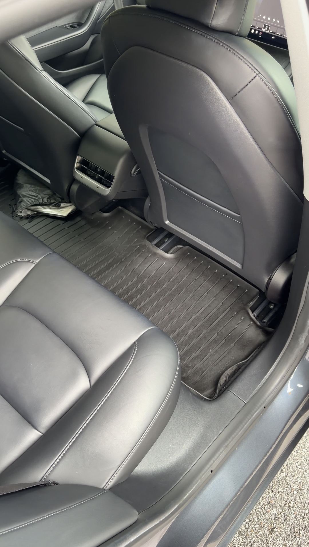 Rear passenger-side footwell of a Tesla Model 3 after cleaning, clean mat and seat back