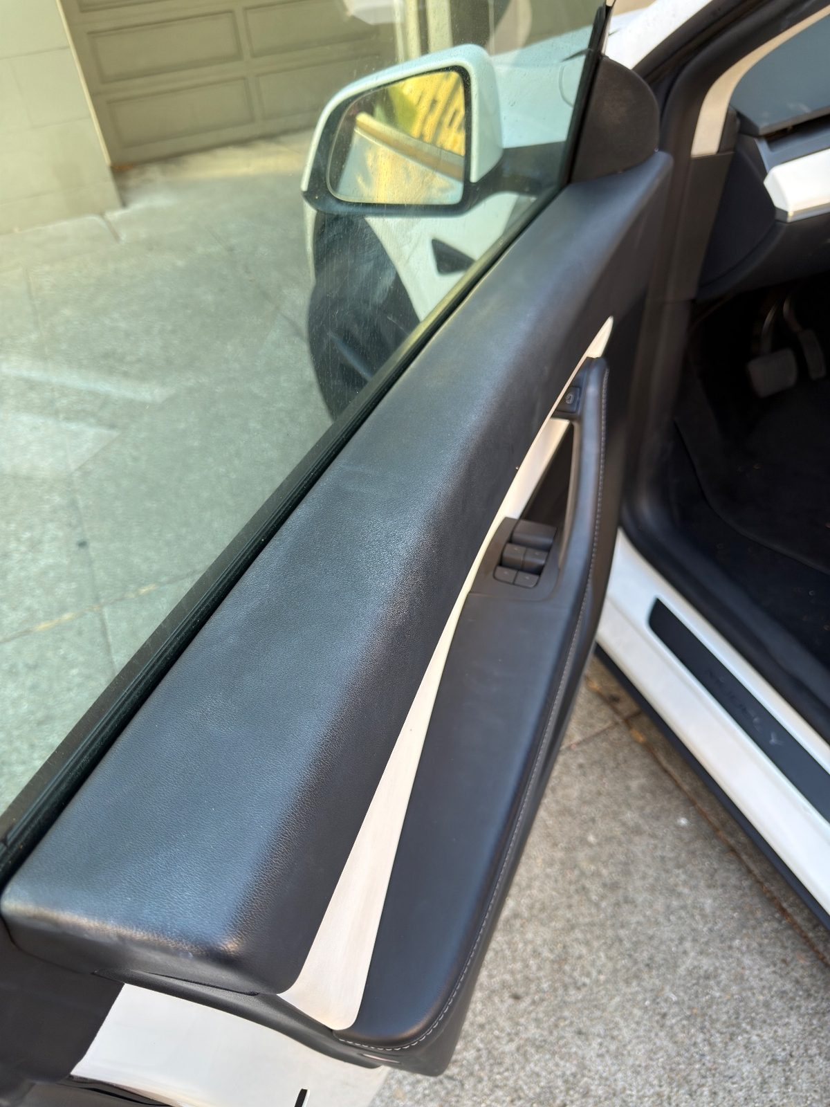 Dusty driver door armrest of a white Tesla Model Y before detailing