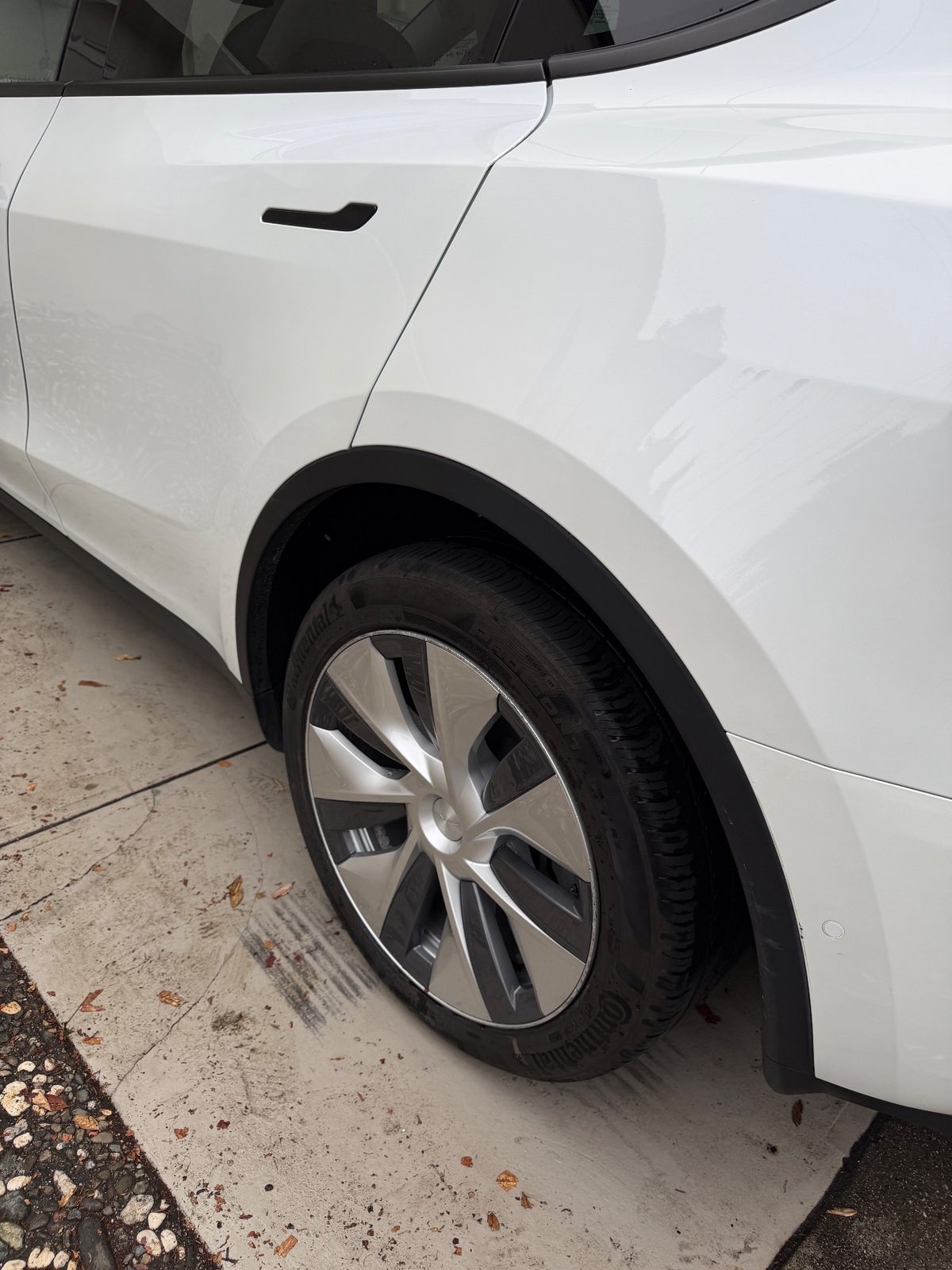 Rear quarter panel and wheel of a white Tesla Model Y after detailing, with a black dressed tyre