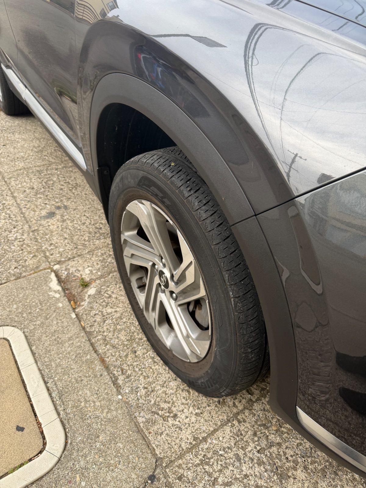 Dusty front fender and wheel arch of a grey Hyundai Santa Fe with a scuffed lower corner, before detailing