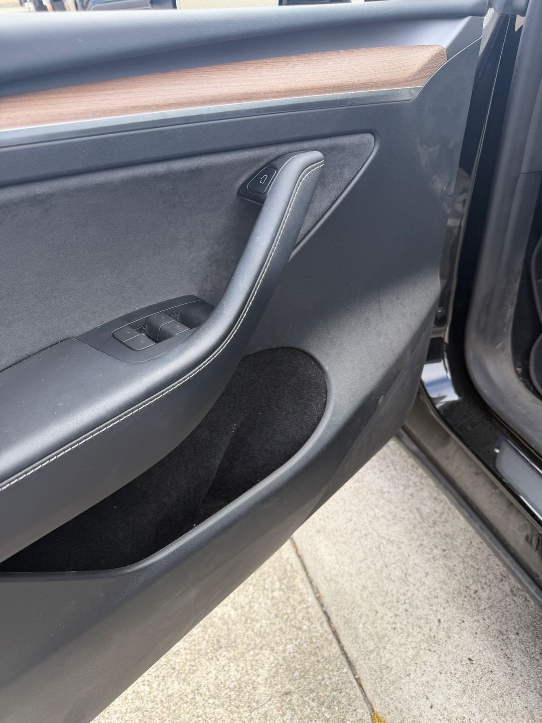 Front door panel of a black Tesla Model Y before detailing, dusty