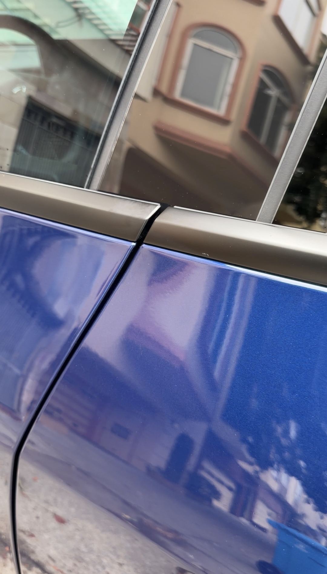 The same door panel of a deep blue Tesla Model Y after detailing, paint and chrome trim clean and glossy.