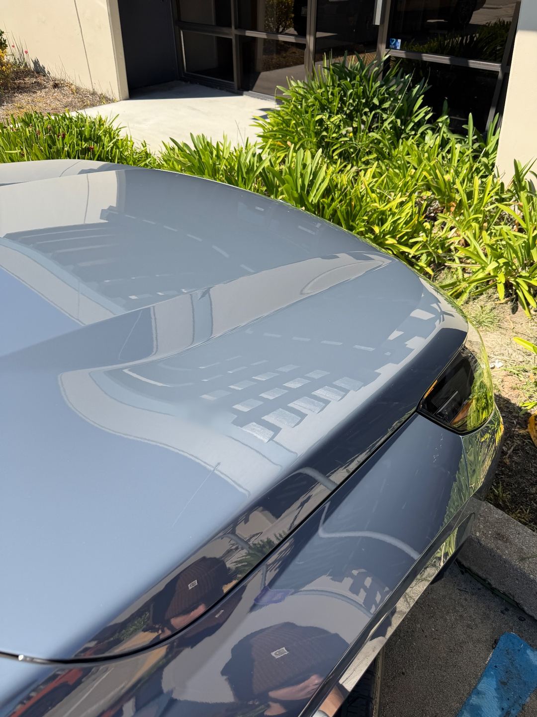 Glossy hood of a grey BMW X1 reflecting the building after a wash