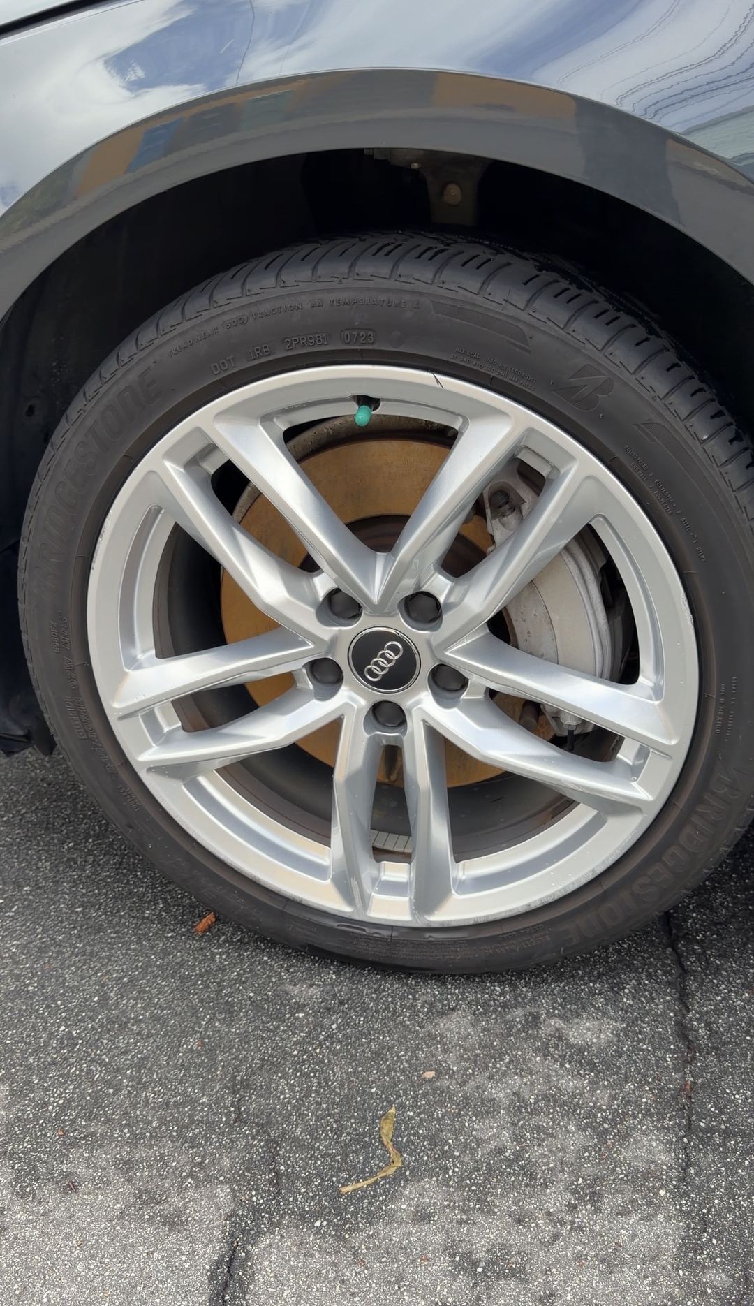 Clean silver twin five-spoke front alloy wheel of a grey Audi A4