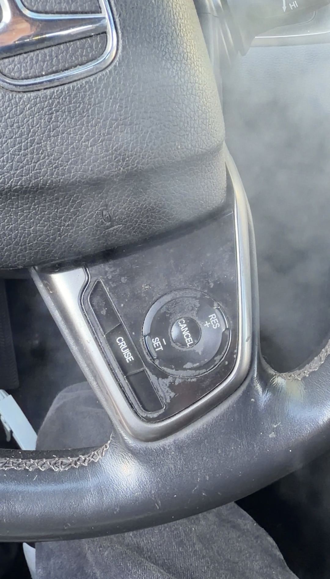 Close-up of a Honda Civic steering wheel cruise-control buttons packed with caked residue before cleaning