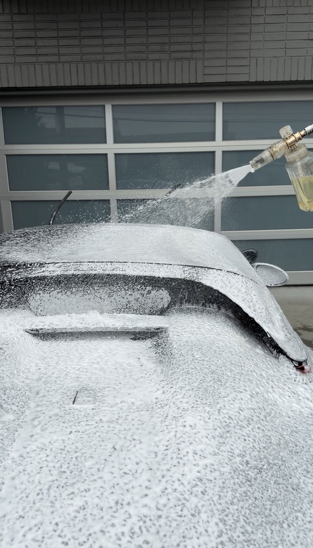 Foam cannon covering a Porsche 718 Spyder RS in thick white snow foam during a mobile detail.