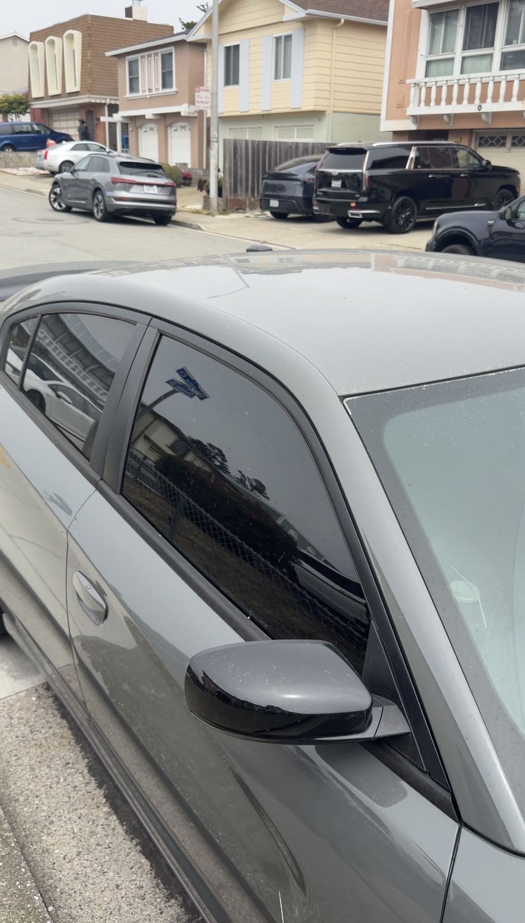 Dusty roof and side glass of a grey Dodge Charger on a residential street before cleaning