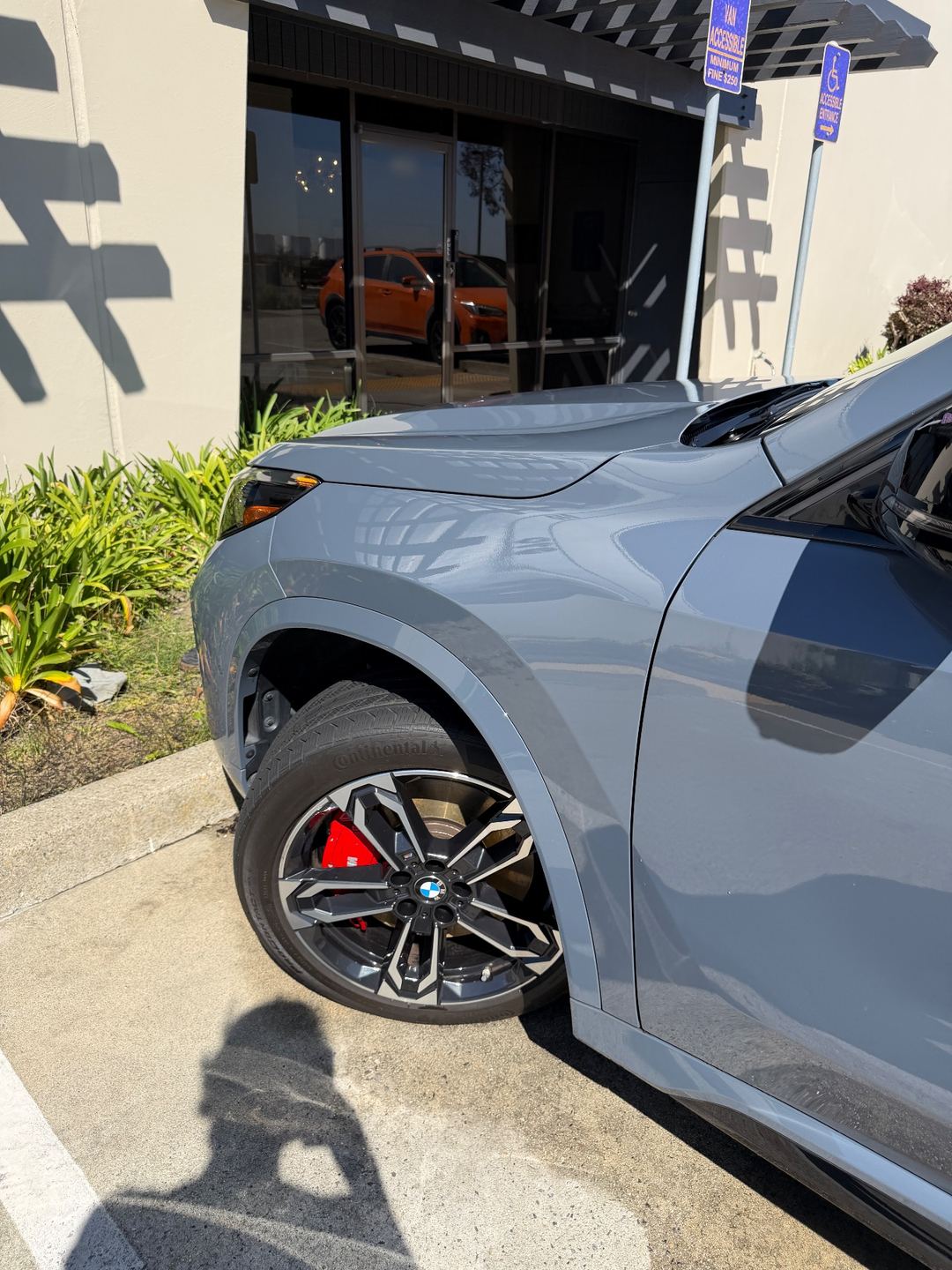 Front of a grey BMW X1 with red brake calipers after a wash