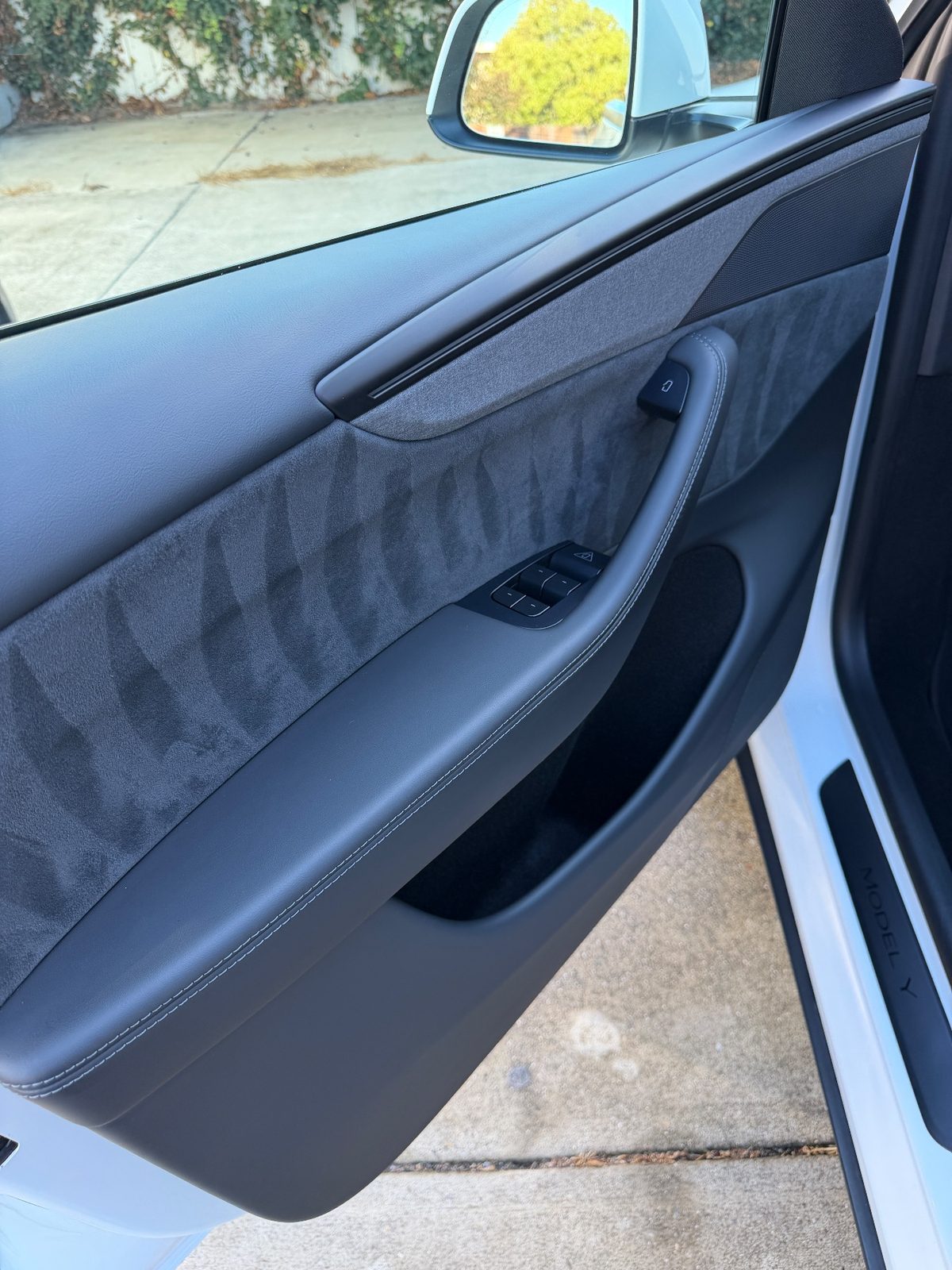 Clean front door panel of a white Tesla Model Y after detailing