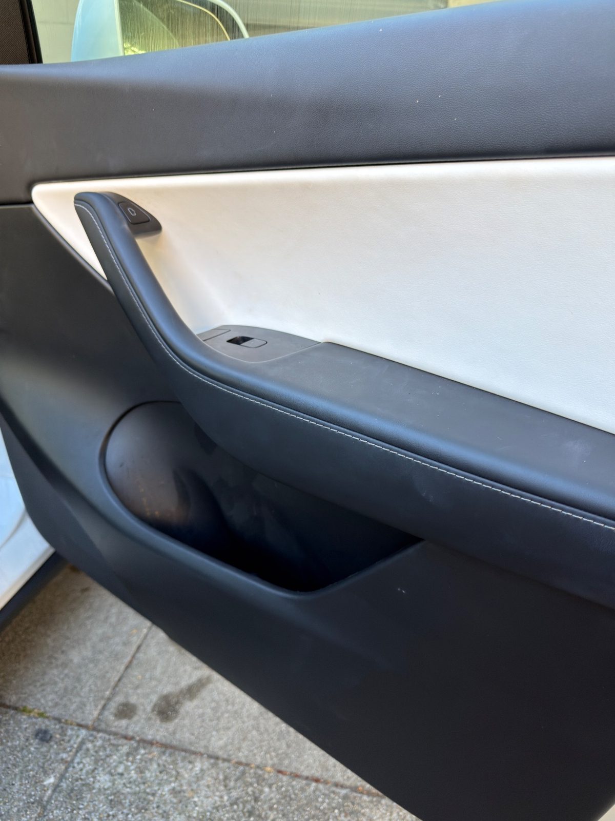 Dusty rear door card inside a white Tesla Model Y before detailing