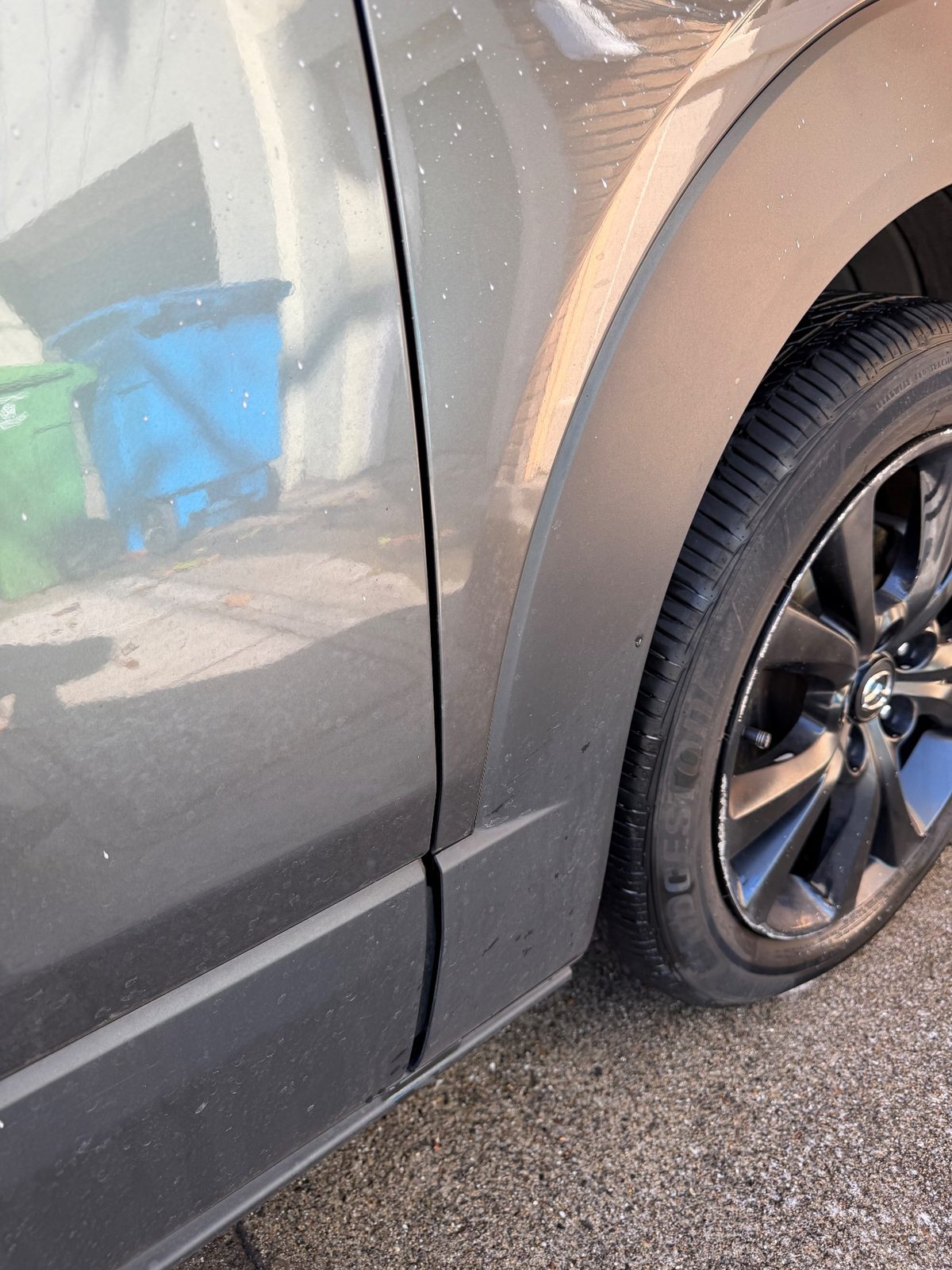 Fender flare of a grey Mazda CX-30 before cleaning, black tar specks on the lower panel