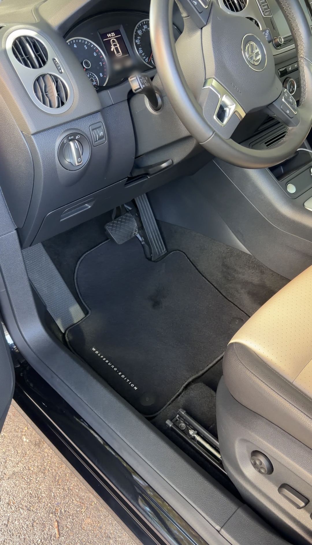 Driver's footwell of a black VW Tiguan Wolfsburg Edition after detailing, the floor mat vacuumed clean with fresh carpet nap.