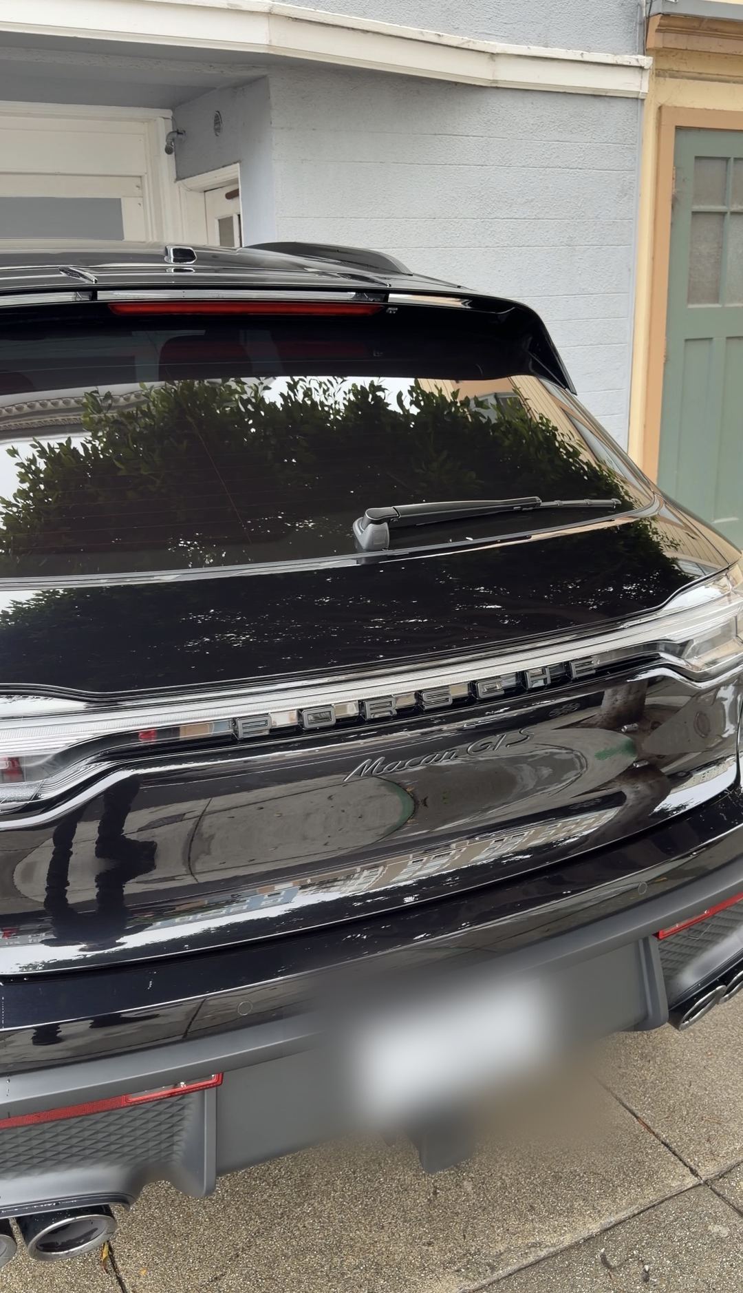 Rear of a freshly washed black Porsche Macan GTS showing the full-width light bar and Macan GTS badge.