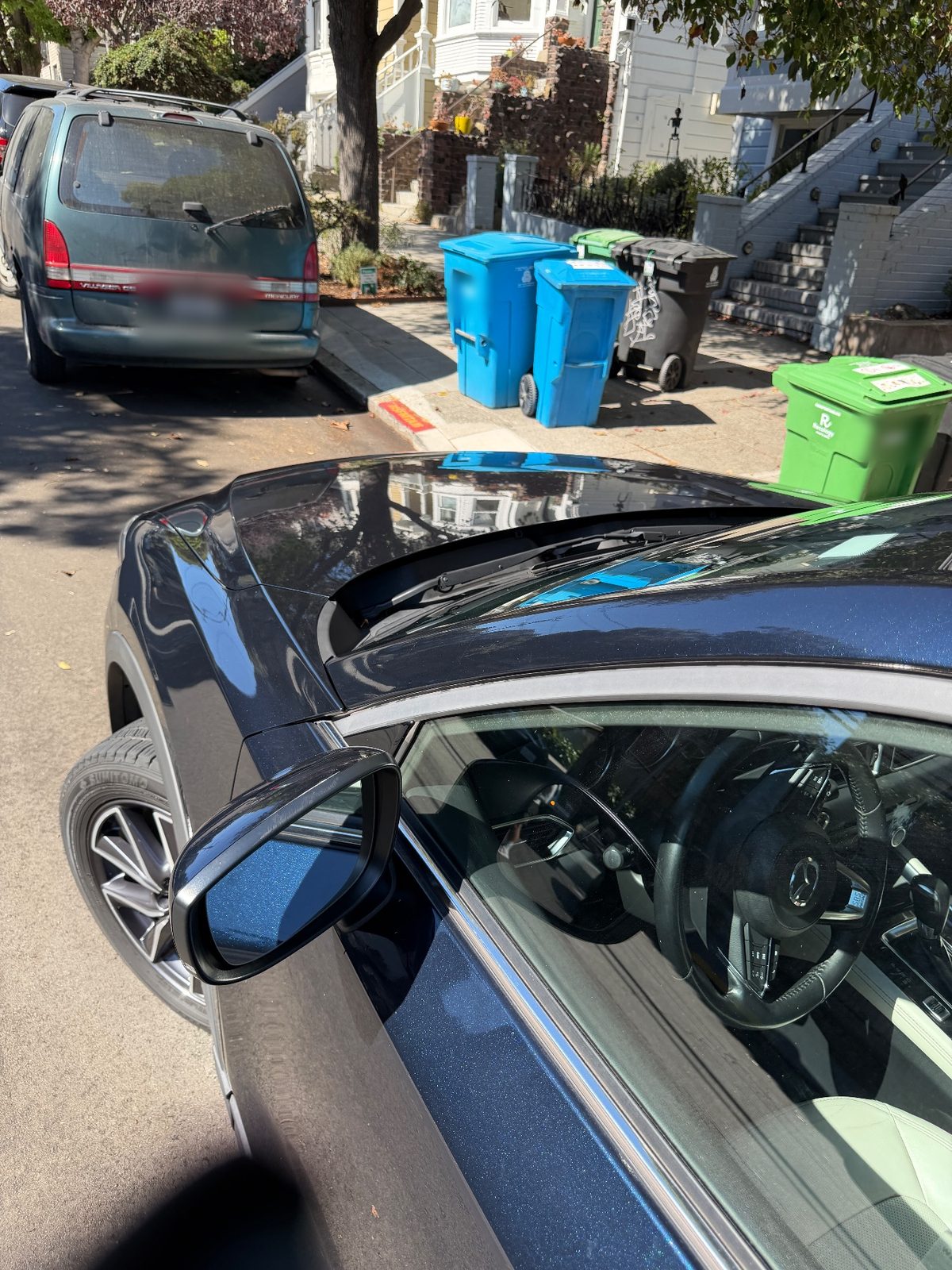 Driver-side wing and mirror of a dark blue Mazda CX-5 after detailing on a residential street
