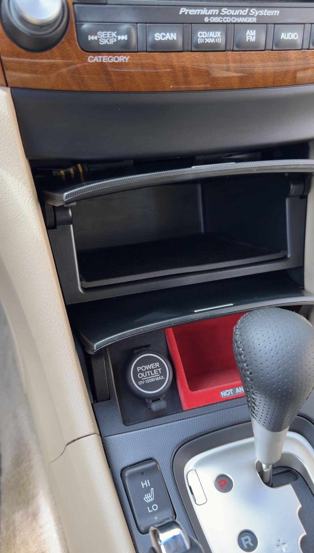 Cleaned centre console and audio stack of an Acura sedan after detailing, with an empty wiped storage bin and dust-free wood trim.