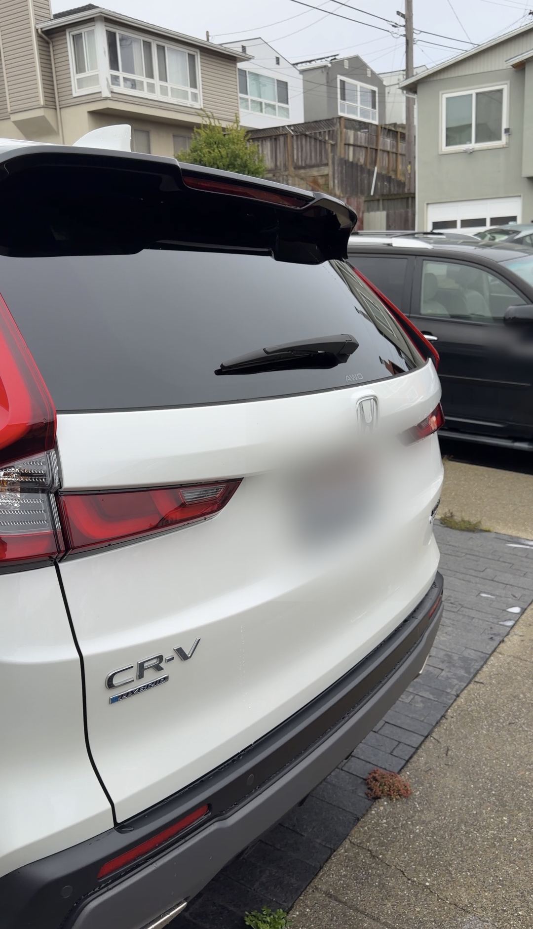 Rear three-quarter view of a clean white Honda CR-V Hybrid parked on a residential street