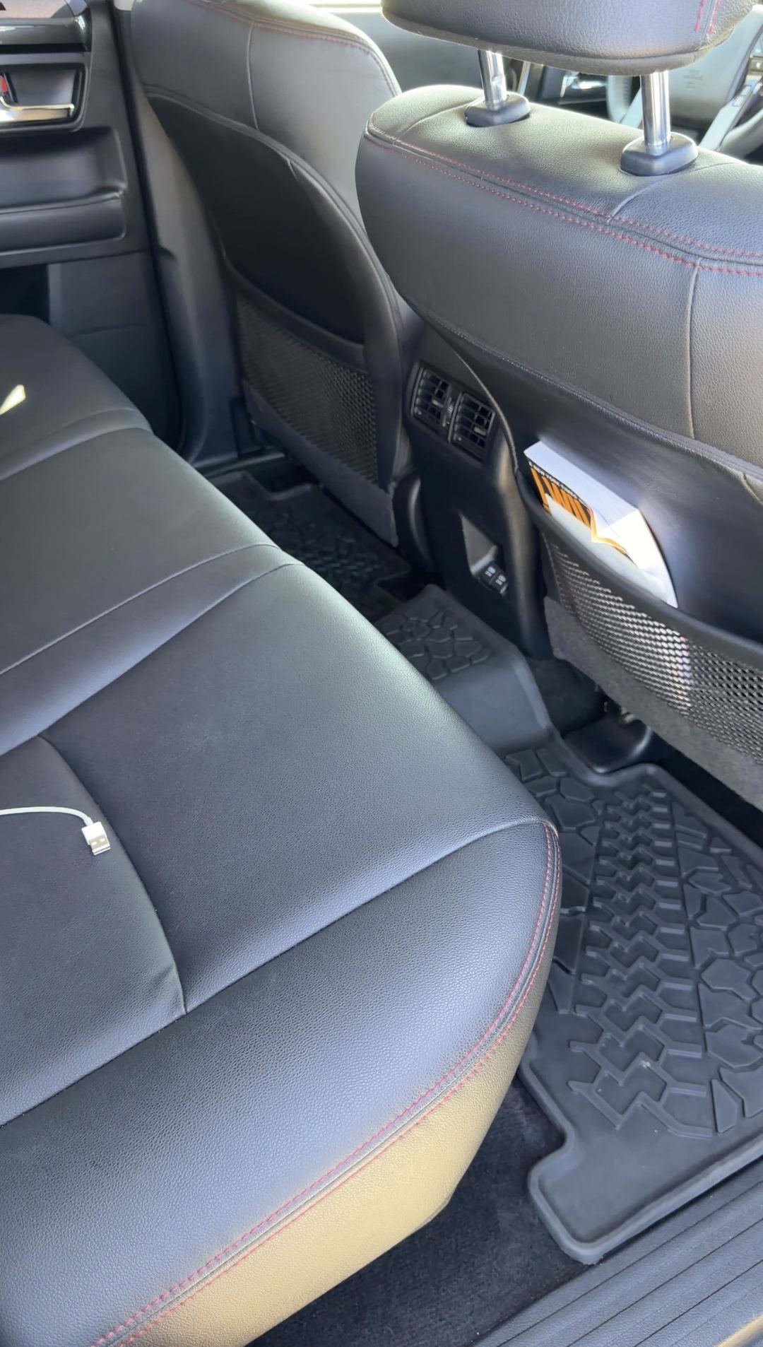 Clean rear passenger footwell, tread-pattern mat and black bench seat in a Toyota 4Runner
