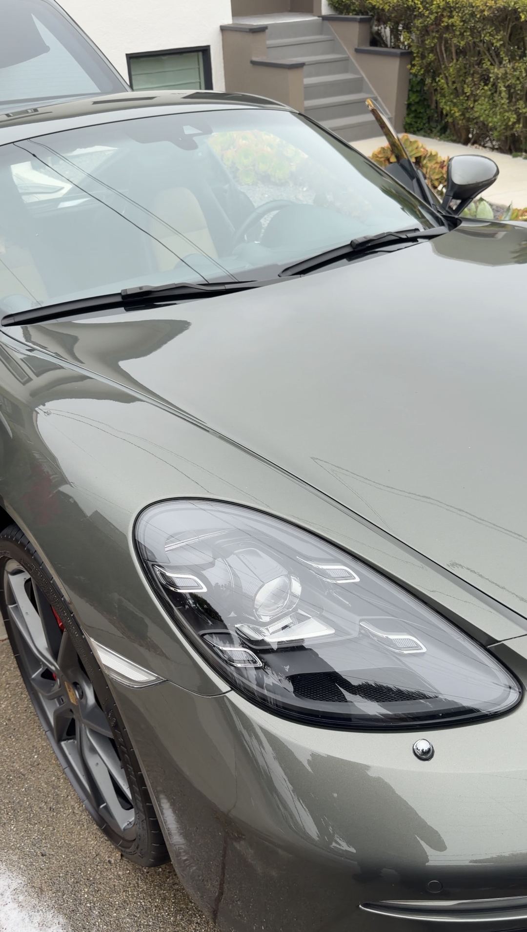 Clean front end and clear headlight of a green Porsche 718 Cayman S after a mobile detail.