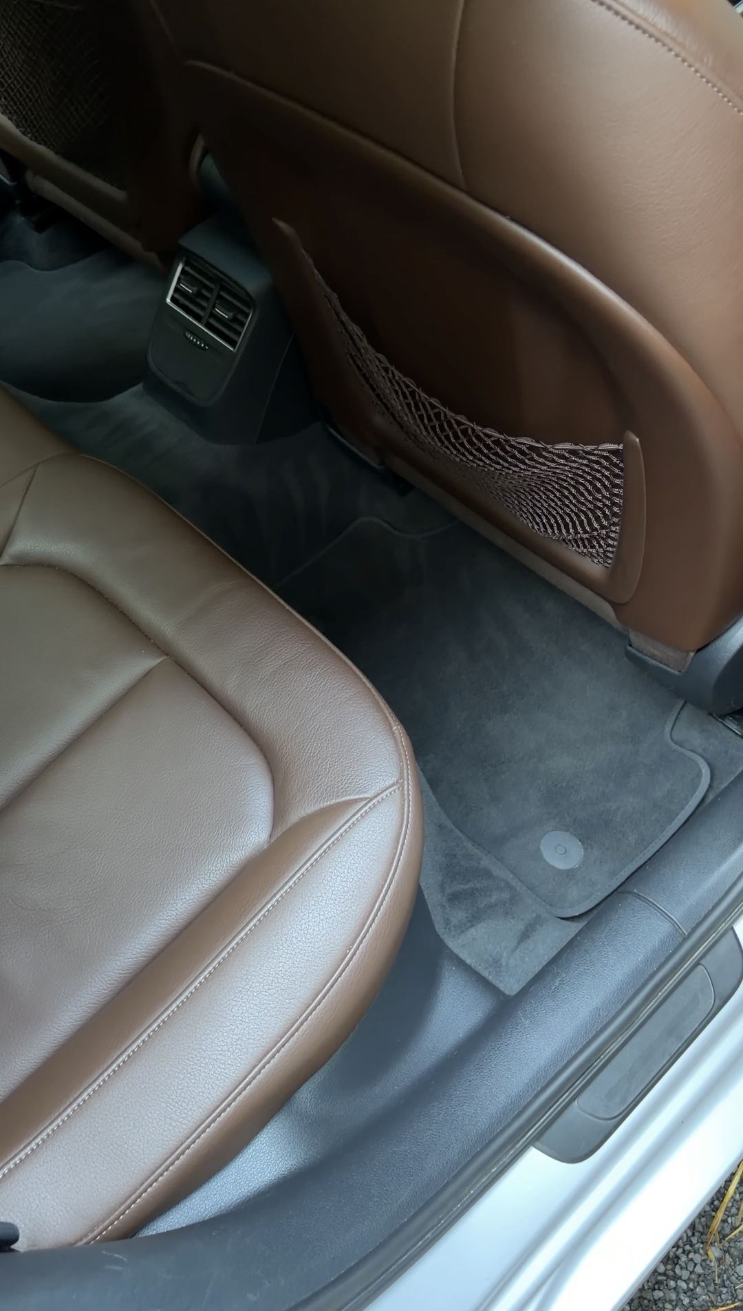 Vacuumed rear floor mat behind the front passenger seat of an Audi A3 with brown leather