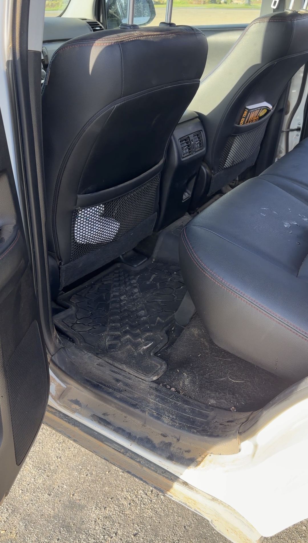 Rear driver-side footwell of a Toyota 4Runner with a dirty tread-pattern mat and muddy sill