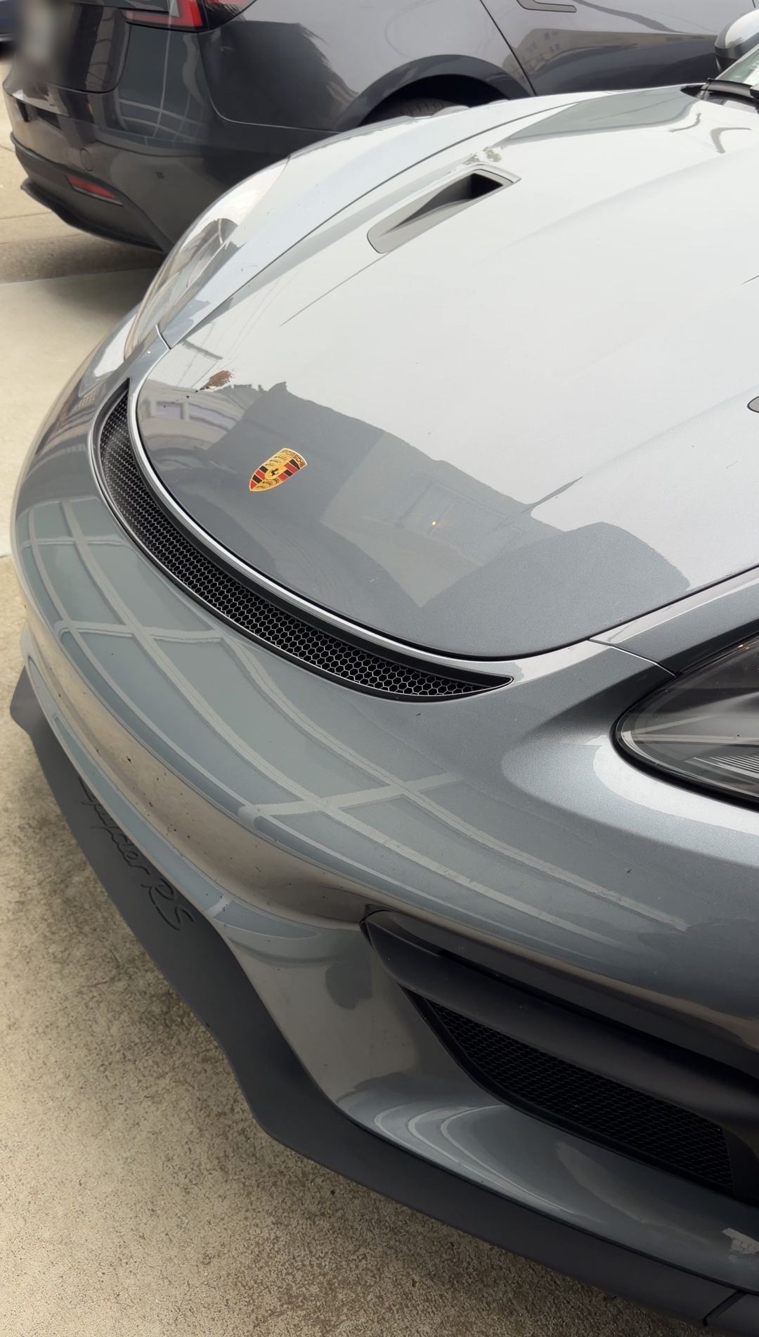 Nose of a grey Porsche 718 Spyder RS before washing, with a bird dropping visible on the bonnet near the crest.