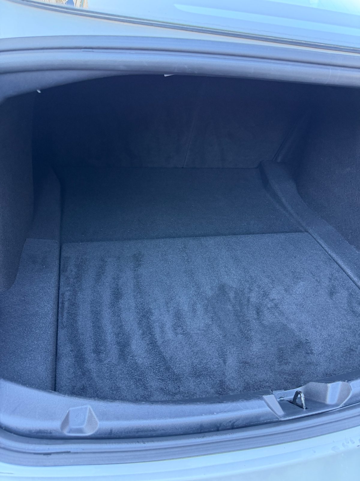 Boot of a white Tesla Model 3 after detailing, with a clean vacuumed carpet