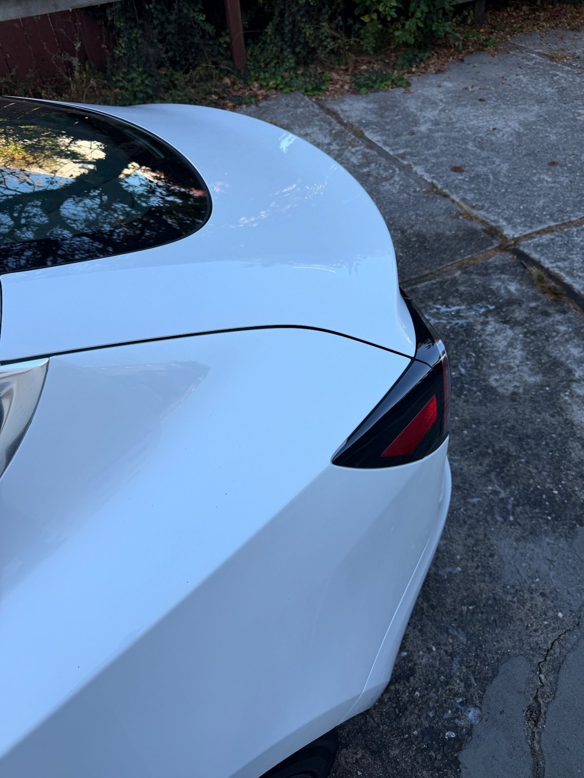 Rear quarter and tail lamp of a white Tesla Model 3 after detailing