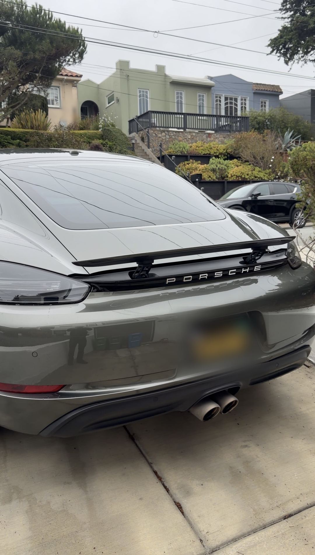 Green Porsche 718 Cayman S seen from the rear with its spoiler raised after a full mobile detail.