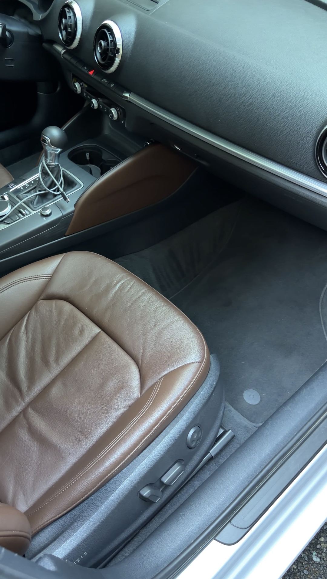 Clean front passenger footwell and console of an Audi A3 with brown leather seats