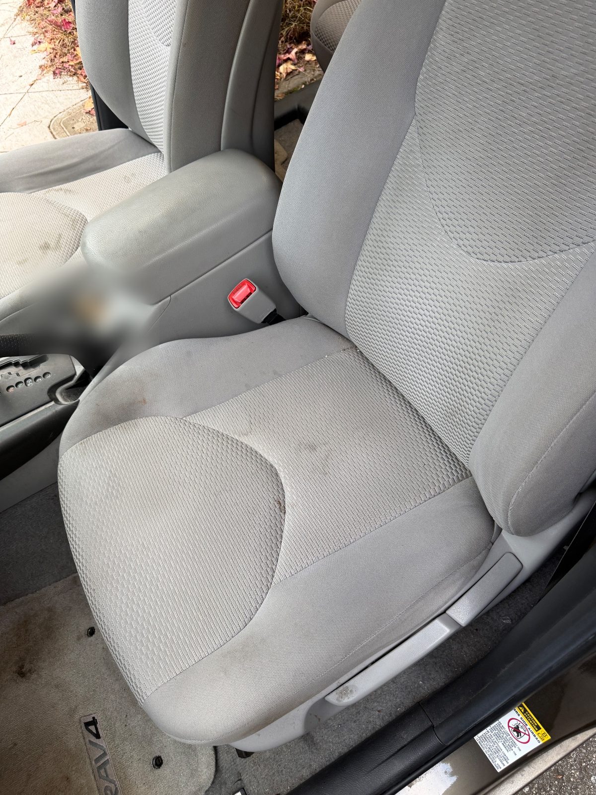 Front cloth seat and console of a 2011 Toyota RAV4 before detailing, stained cushion