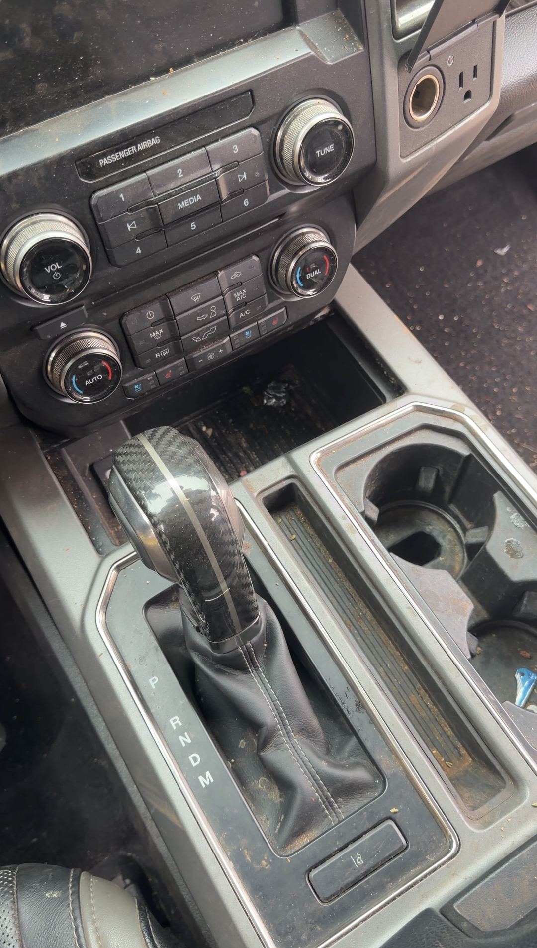 Centre console and cupholders of a Ford F-150 Raptor with debris before cleaning