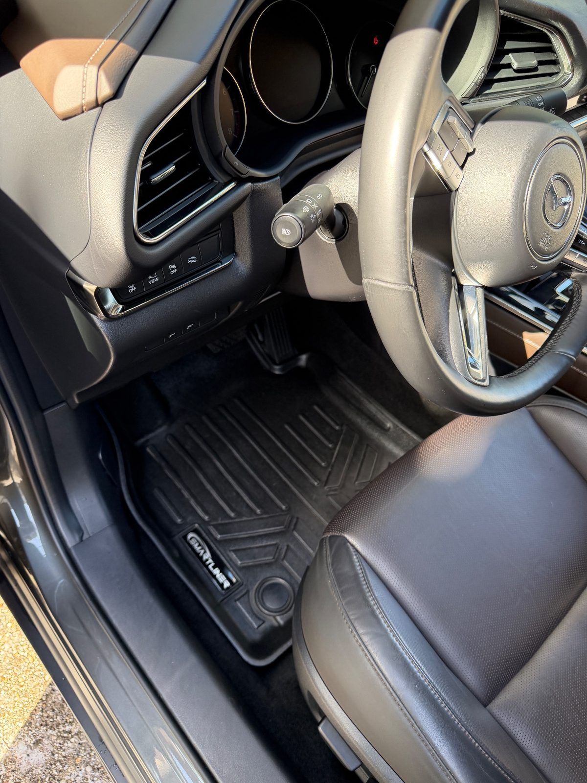 Driver footwell of a grey Mazda CX-30 after detailing, clean liner and steering wheel