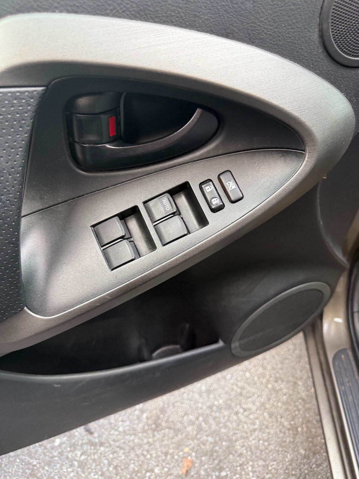 Driver door panel of a 2011 Toyota RAV4 before cleaning, dusty switch bank