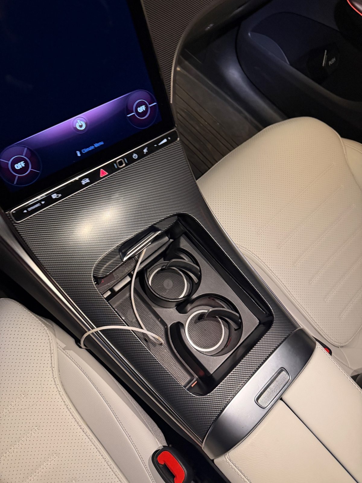 Centre console of a white Mercedes GLC before cleaning, dusty cup holders with a white cable