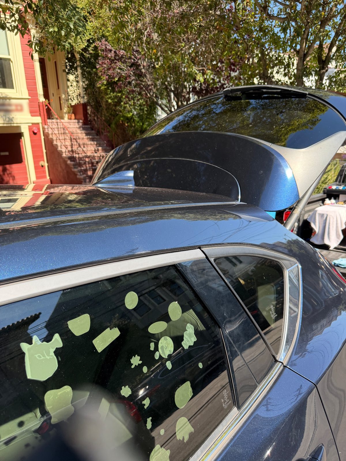 Roof and raised tailgate of a dark blue Mazda CX-5 after washing, parked on a residential street
