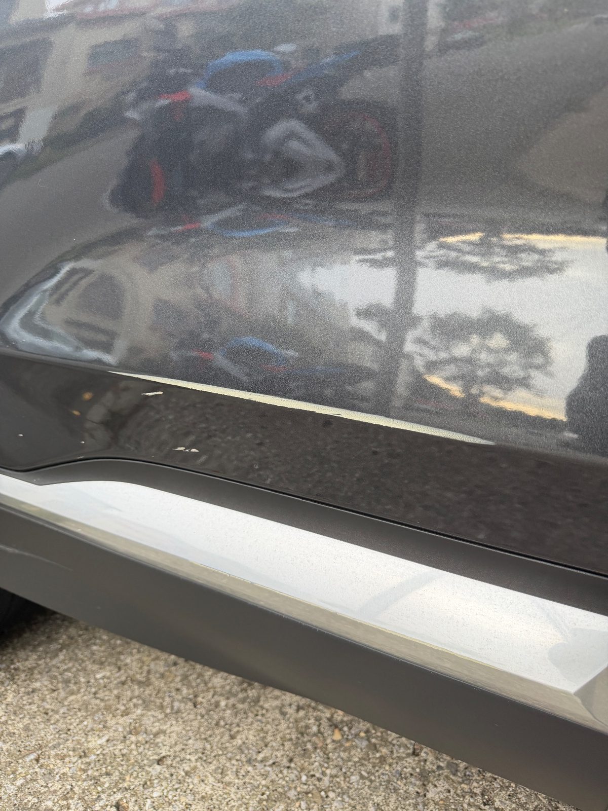 Small paint chips on the lower rear door of a grey Hyundai Santa Fe before detailing