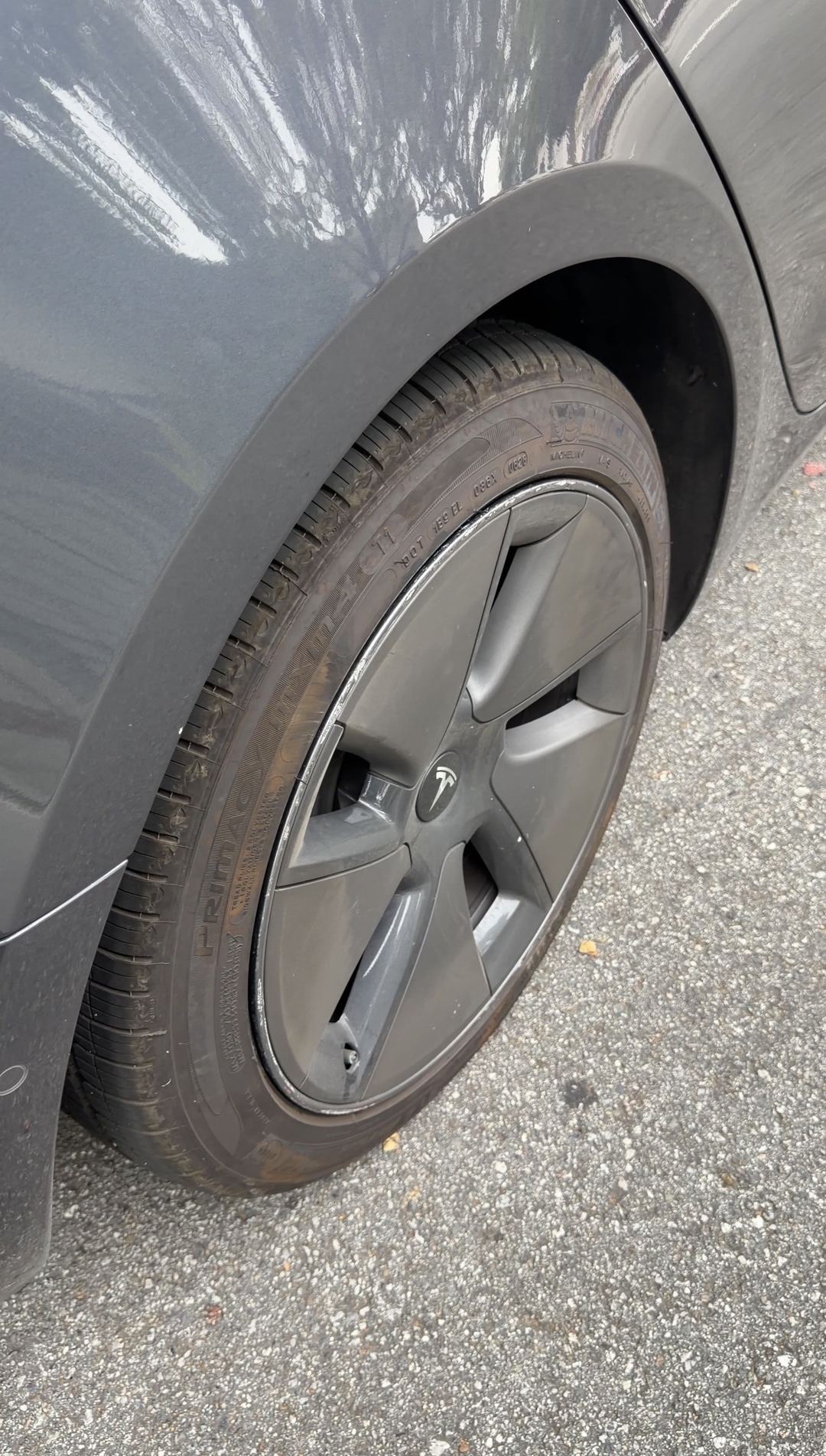 Tesla Model 3 rear wheel before cleaning, grey Aero wheel cover and browned Michelin tyre