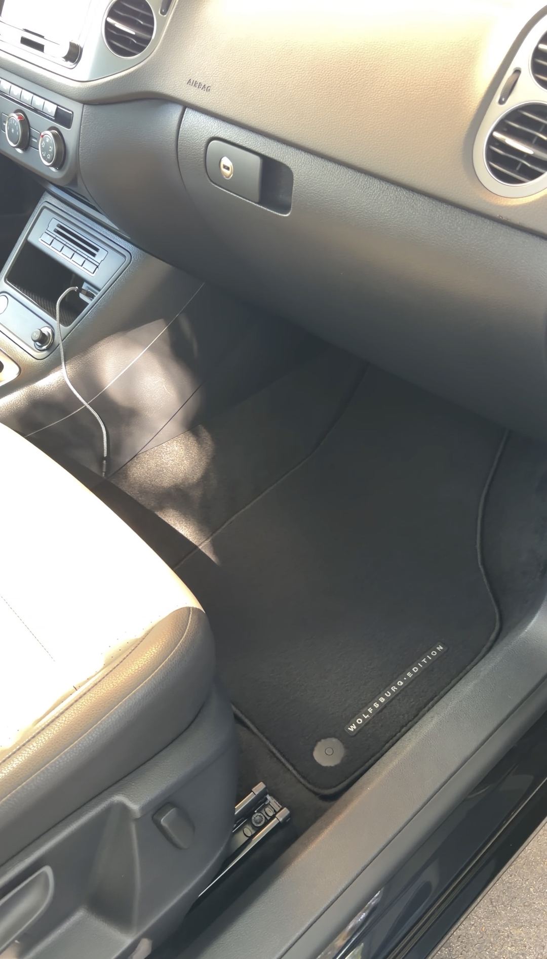 Front passenger footwell of a black VW Tiguan after detailing, the Wolfsburg Edition mat vacuumed clean.