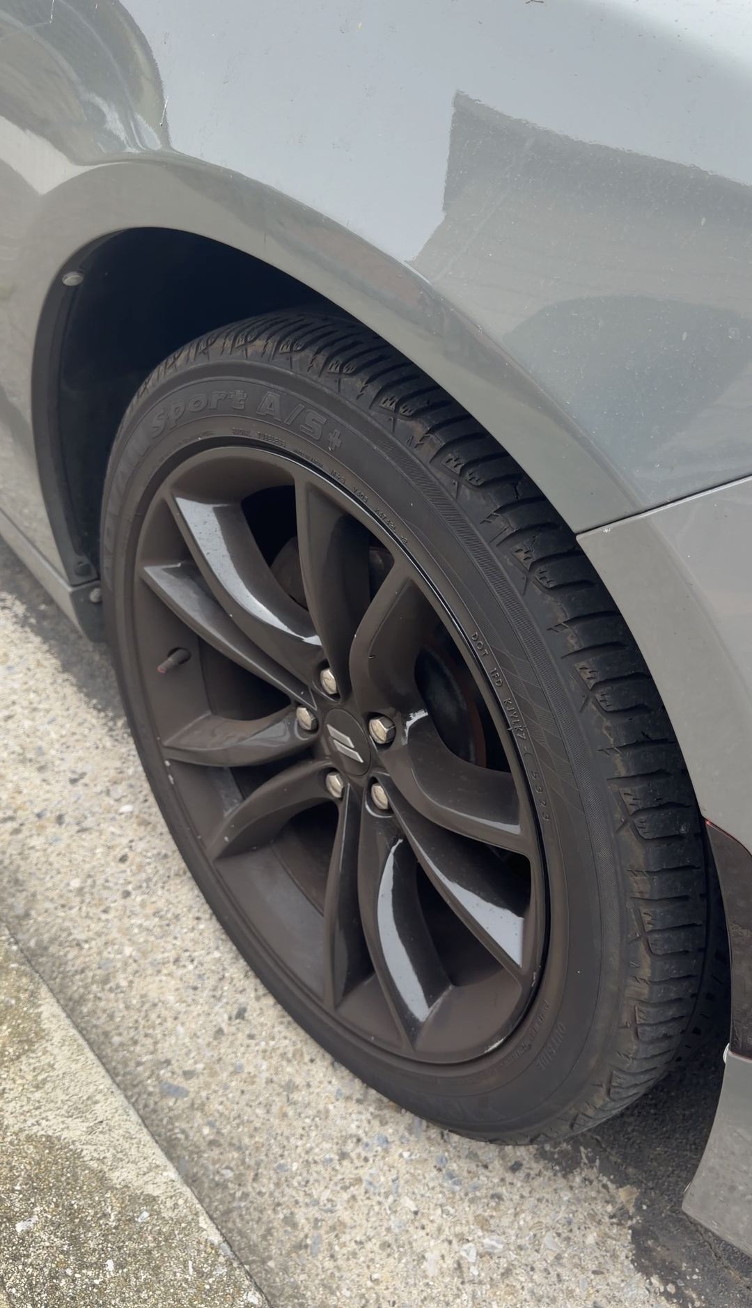 Dodge Charger black split-spoke wheel with brake dust beside the kerb before cleaning