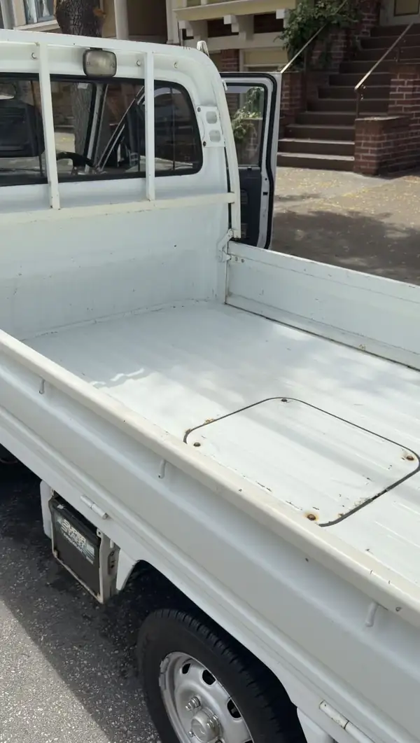 Clean ribbed steel cargo bed of a Honda Acty kei truck after washing, bed floor bright in sunlight.