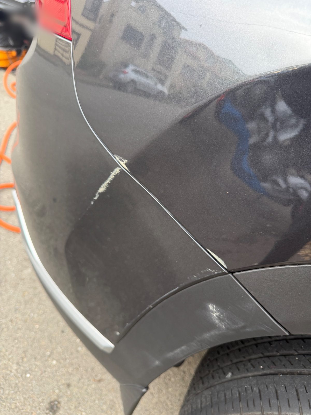 Scuffs and paint transfer on the rear bumper corner of a grey Hyundai Santa Fe before detailing