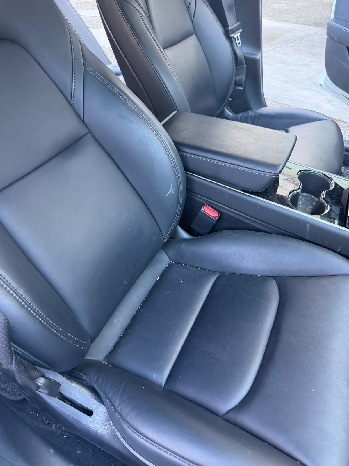 Passenger seat of a white Tesla Model 3 before detailing, with crumbs in the seams