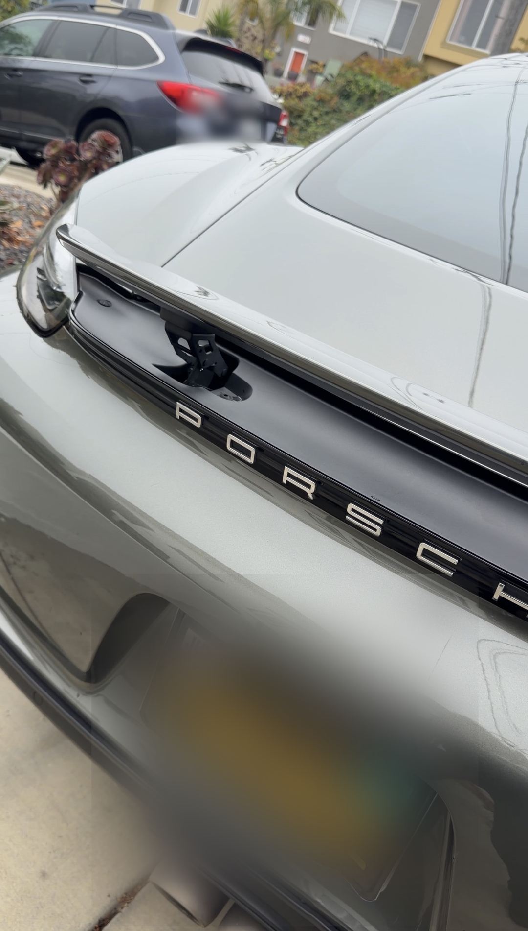 Cleaned gloss black rear badge band of a Porsche 718 Cayman S after detailing.