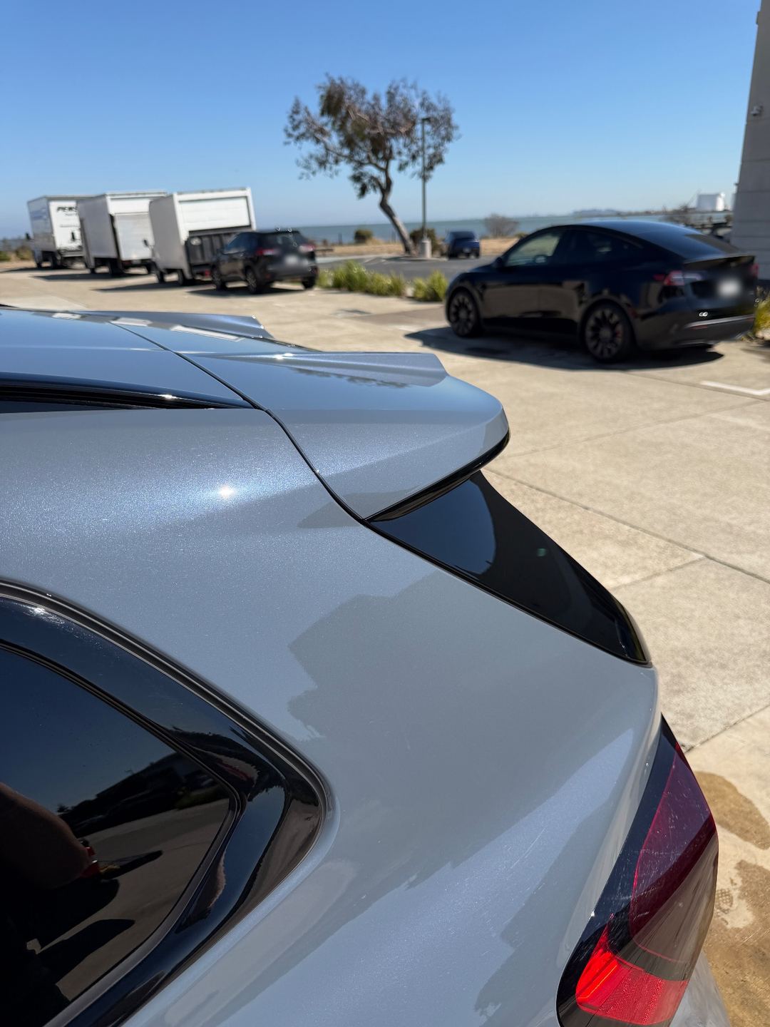Roof spoiler of a grey BMW X1 after washing, with the bay in the background