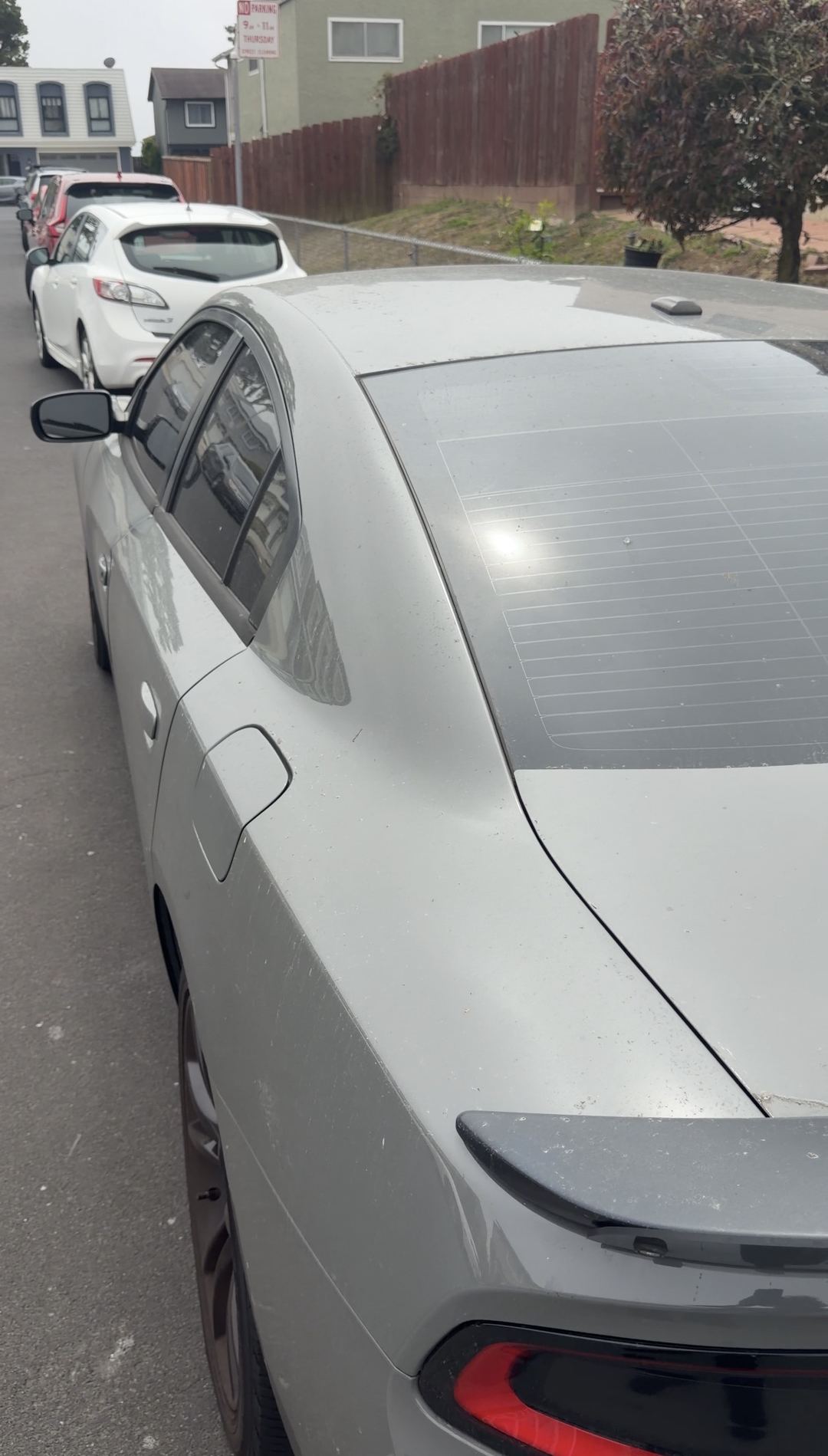 Grey Dodge Charger rear window and roof with dust film before an exterior detail