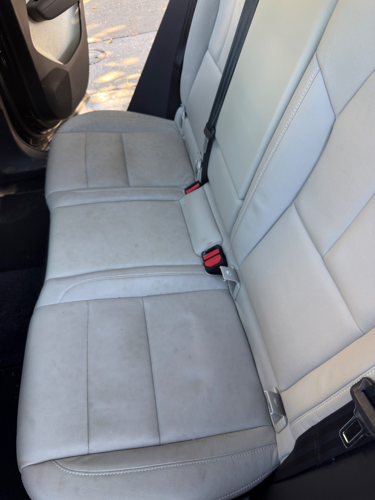 Rear bench seat of a Volvo XC40 with yellow-brown spotting and grime on the light leather before detailing
