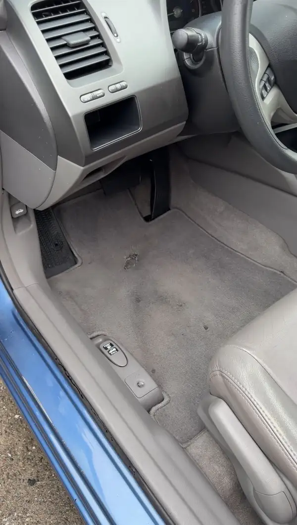 Cleaned driver footwell of a Honda Civic with vacuumed carpet and a wiped door sill.