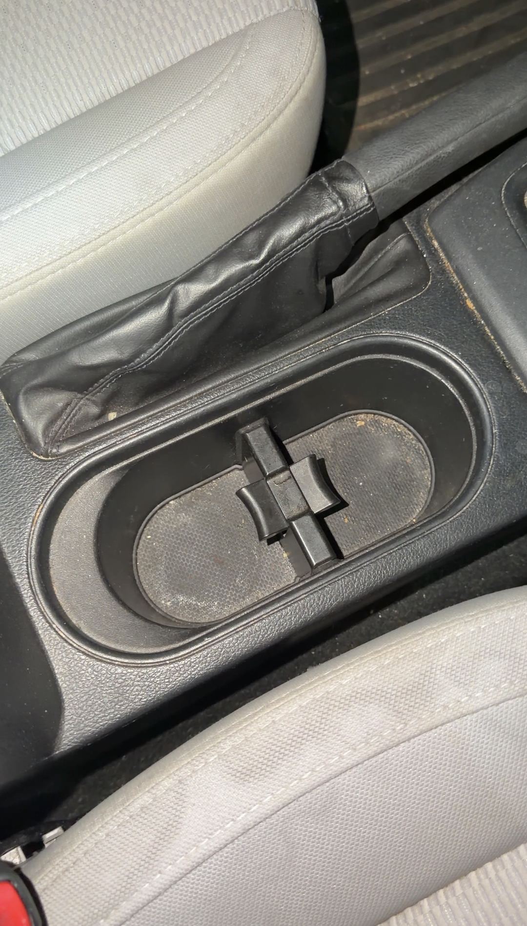 Centre console of a blue Subaru Forester before detailing, dust and crumbs in the twin cupholders beside the manual handbrake.